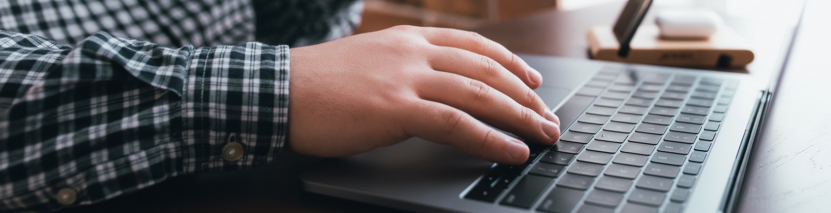 Man working at the laptop with a cup of coffee at home. Blurred background